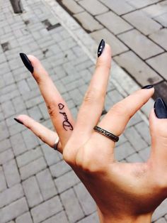 a woman's hand with black nail polish holding up the peace sign on her fingers