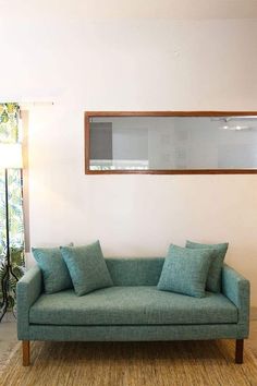 a living room with a blue couch and some pillows on the floor in front of a window