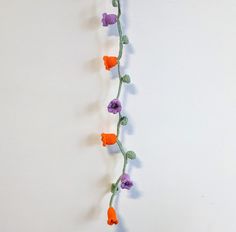 an orange and purple flower is hanging on the wall