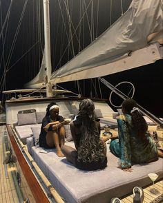 three women sitting on the deck of a sailboat