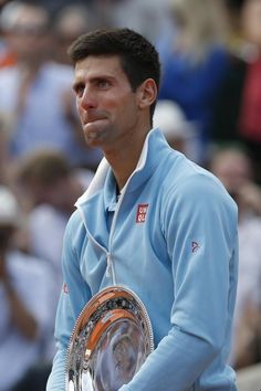 a man holding a tennis racquet on top of a tennis court in front of a crowd