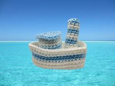 a knitted boat floating in the middle of the ocean with blue sky and water behind it