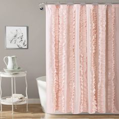 a pink shower curtain with ruffles on it in a bathroom next to a white tub