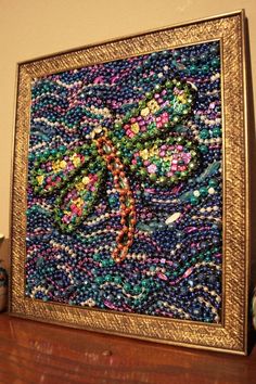 a beaded dragonfly sitting on top of a wooden table next to a vase