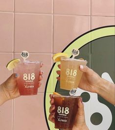 two people holding up drinks in front of a pink tile wall with the number 818 on it