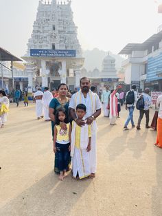 a man and two children standing in front of a temple