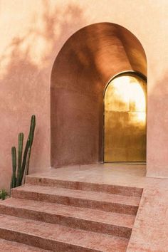 an open door on the side of a pink building with steps leading up to it