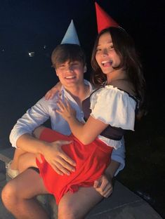 a man and woman sitting next to each other wearing party hats