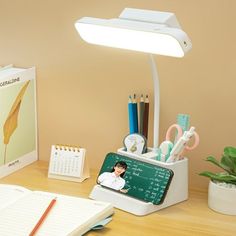 a desk with a lamp, notebook and various office supplies