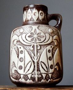 a ceramic vase sitting on top of a wooden table