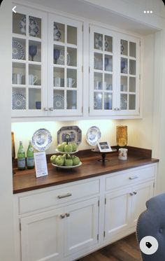 a kitchen with white cabinets and wooden counter tops, blue chairs and plates on the table