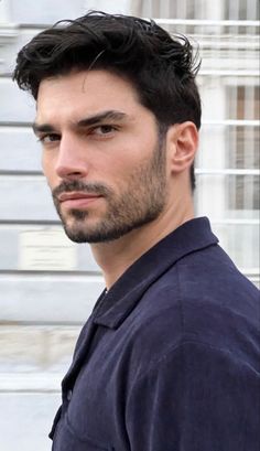 a close up of a person wearing a blue shirt and black hair with a building in the background