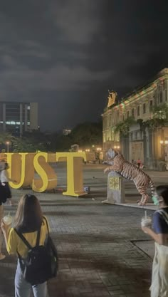 people are walking around in front of a sign that says trust with a tiger on it