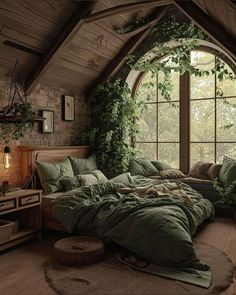 a large bed sitting under a window next to a wooden floor covered in green blankets