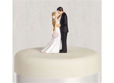 a bride and groom figurine on top of a cake