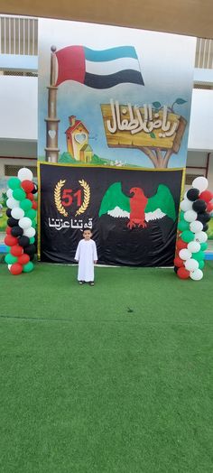 a man standing in front of a giant balloon arch with flags and balloons on it