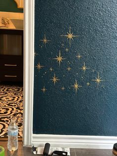 a wall with gold stars painted on it in a room next to a bottle of water