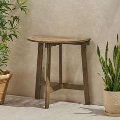 a wooden stool sitting next to a potted plant