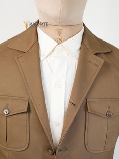 This custom brown cotton safari jacket features button closure and patch pockets, blending functionality with style. Ideal for travel, business, or formal occasions, it offers a rugged yet refined look. A perfect gift for men who appreciate versatile, tailored attire. At Magnate Artisans, we believe that fashion is an art form, and your wardrobe is a canvas. Our custom-made clothing service is designed to bring your unique vision to life, offering an unparalleled level of personalization for bot Classic Fitted Utility Jacket With Welt Pockets, Lapel Collar Gabardine Blazer With Pockets, Classic Fitted Utility Jacket With Patch Pockets, Gabardine Blazer With Lapel Collar And Pockets, Classic Cotton Sport Coat With Flap Pockets, Classic Fitted Utility Jacket With Flap Pockets, Fitted Classic Brown Utility Jacket, Classic Fitted Brown Utility Jacket, Classic Khaki Sport Coat With Patch Pockets