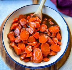 a bowl filled with cooked carrots on top of a wooden spoon