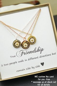 two gold necklaces with the words friends and compass charms on them are sitting in a box