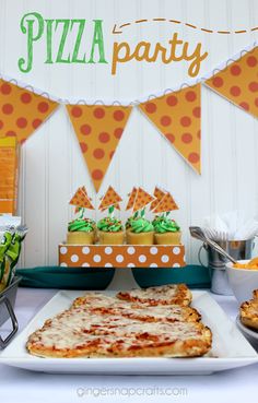 a table topped with pizza and cupcakes on top of plates