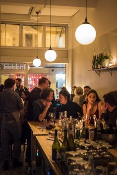 a group of people sitting at a bar with wine glasses