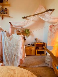 a room with some clothes hanging from the ceiling and other items on the table in front of it