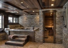 a bathroom with stone walls and steps leading up to the jacuzzi bathtub