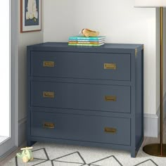 a blue chest of drawers in a room with a lamp and pictures on the wall