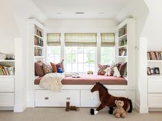 a stuffed horse sitting on top of a white bench next to a book shelf filled with books