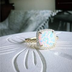 an opal and diamond ring sits on a table