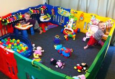 two toddlers playing in a playpen with toys on the floor and around them