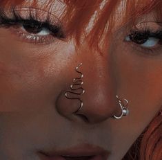 a woman with red hair and piercings on her nose