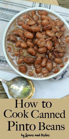 a white bowl filled with pinto beans on top of a table next to a spoon