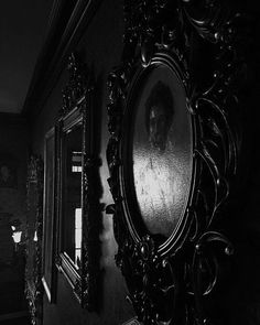 a black and white photo of a man's face in an ornate framed mirror