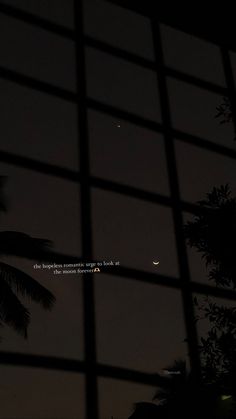 the moon is seen through a window with trees in the foreground and an airplane flying overhead