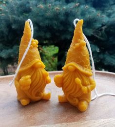 two yellow figurines sitting on top of a wooden table next to each other