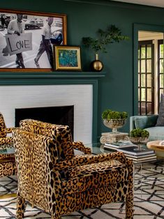 a living room with green walls and leopard print chairs in front of the fire place