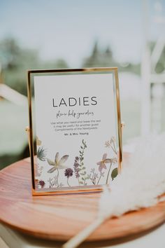 a sign that is sitting on top of a wooden table next to a white feather