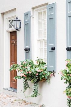 two blue shuttered windows with flowers in front of them and a light on the outside