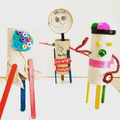 three different colored toothbrush holders with faces and hands on them, one holding a pencil