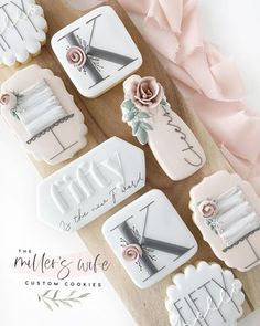 decorated cookies on a wooden board with pink flowers and ribbon around the edges that spell it's time to cut