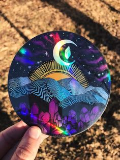 a hand holding up a sticker with an image of the moon and stars on it