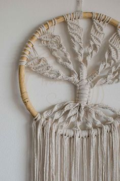 a white wall hanging with some tassels on it's sides and a tree in the middle