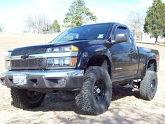 a black truck parked on top of a dirt field