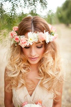 a woman with long blonde hair holding a bouquet of flowers and wearing a flower crown