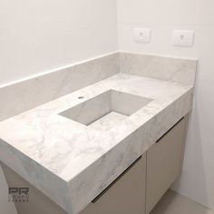 a bathroom counter with a white marble sink in the middle and light switch on the wall