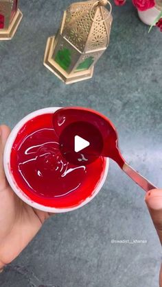 a person holding a spoon with red liquid in it