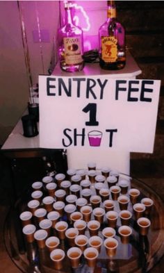 there is a sign that says entry fee 1 shot on the table with cups in front of it